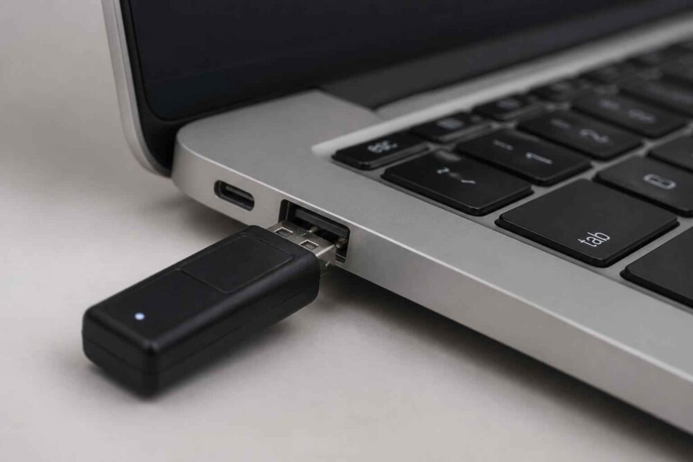 Czarny pendrive podłączony do bocznego portu USB srebrnego laptopa