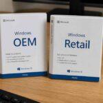 Dwa pudełka z licencjami Windows OEM i Retail na drewnianym biurku